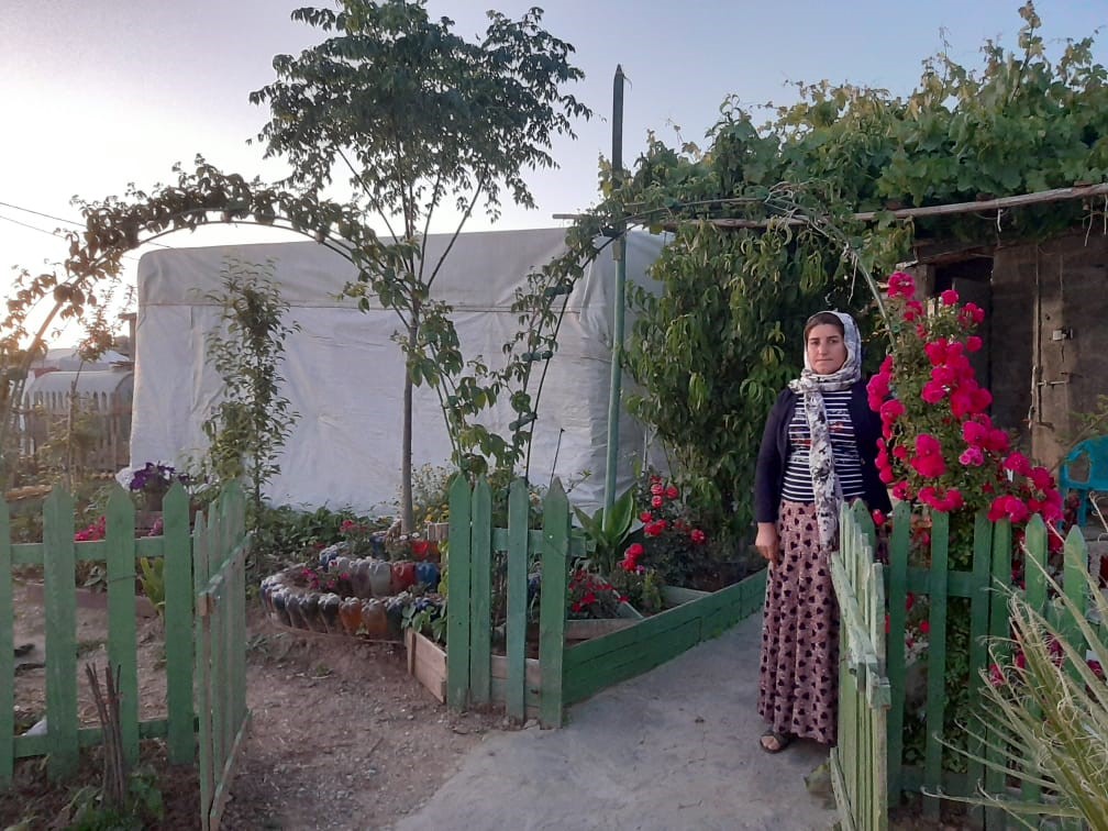 Donne al cancello del giardino con fiori rossi